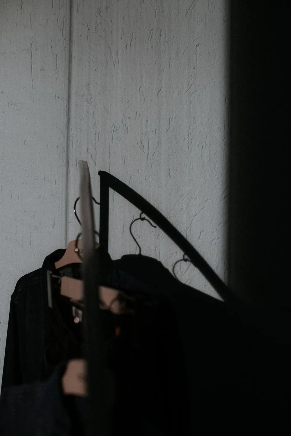 Reference photo 3: black garments on hangers in a dark interior — abayas & kaftans we manufacture and export in bulk to United Arab Emirates