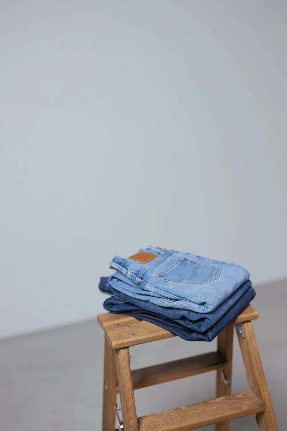 Reference photo 4: stack of folded jeans on a wooden stool — jeans we manufacture and export in bulk to South Africa