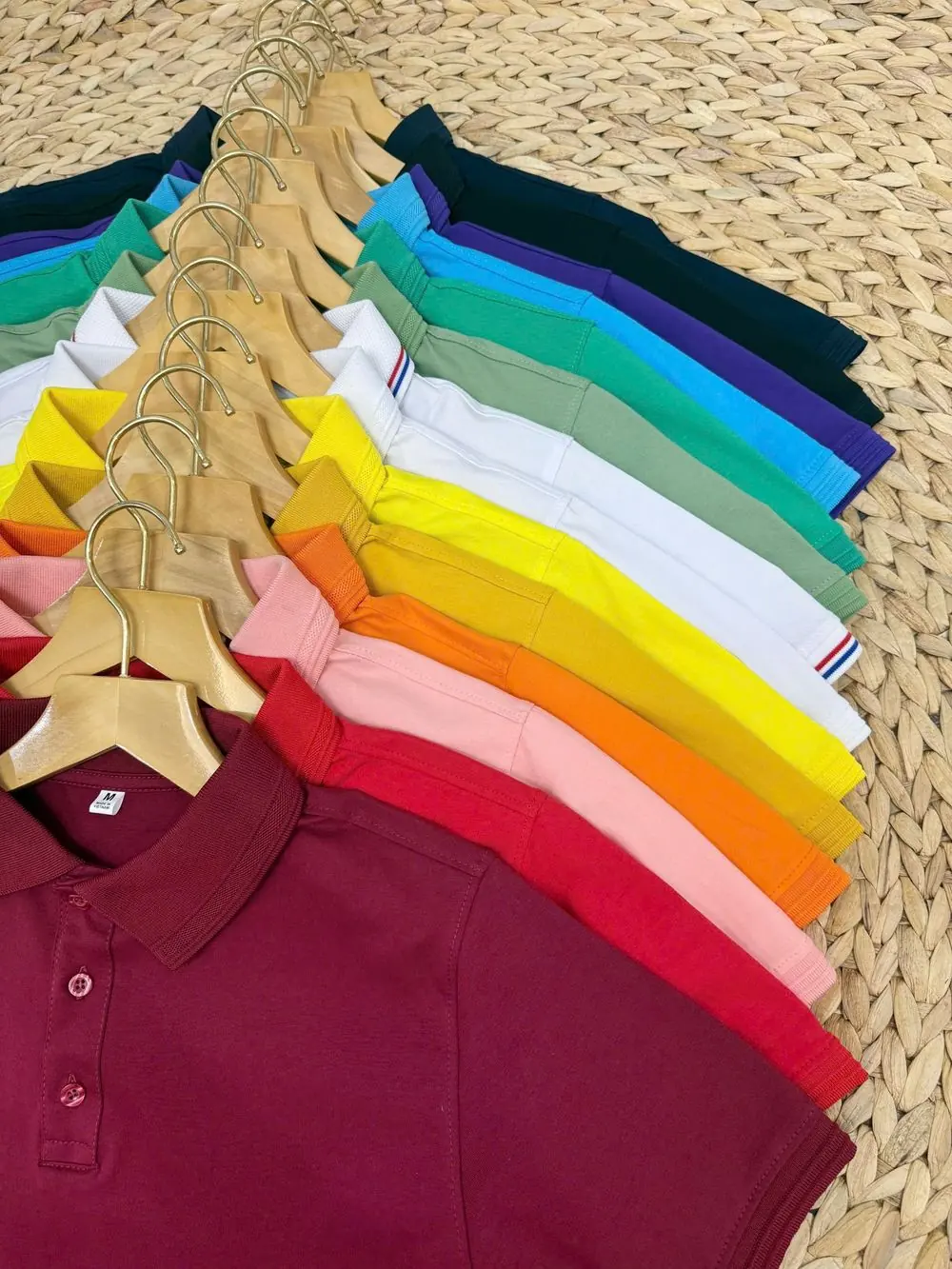 Reference photo 2: rainbow of polo shirts on hangers — polo t-shirts we manufacture and export in bulk to Qatar