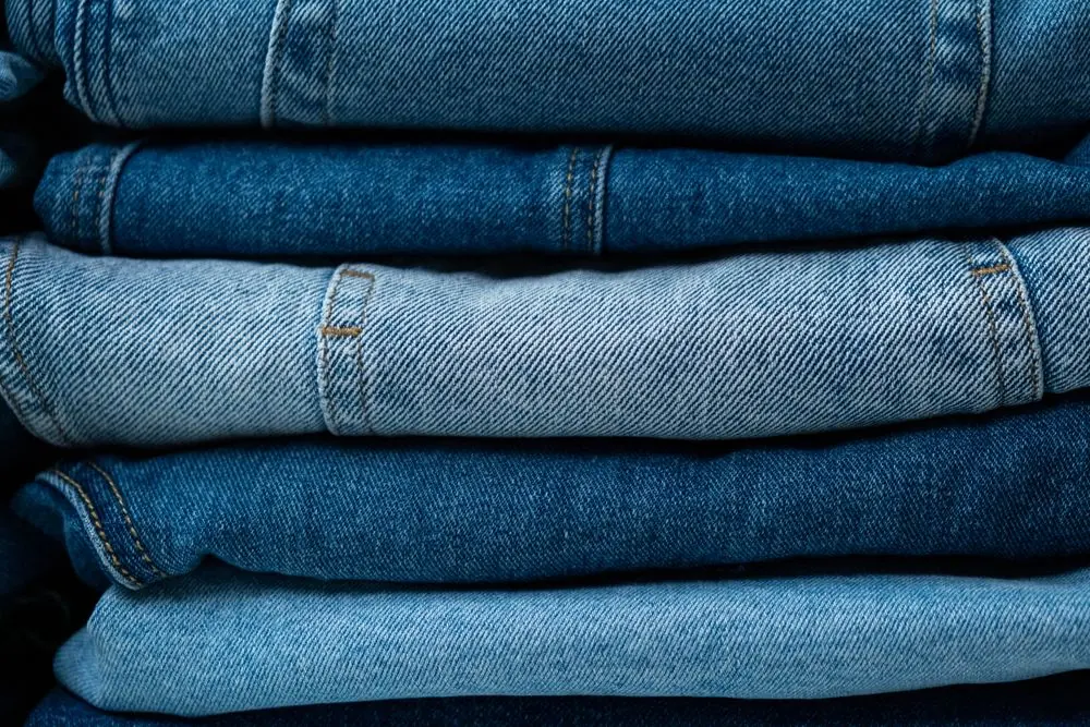 Reference photo 5: stack of folded trousers in indigo shades — trousers & cargo pants we manufacture and export in bulk to Saudi Arabia